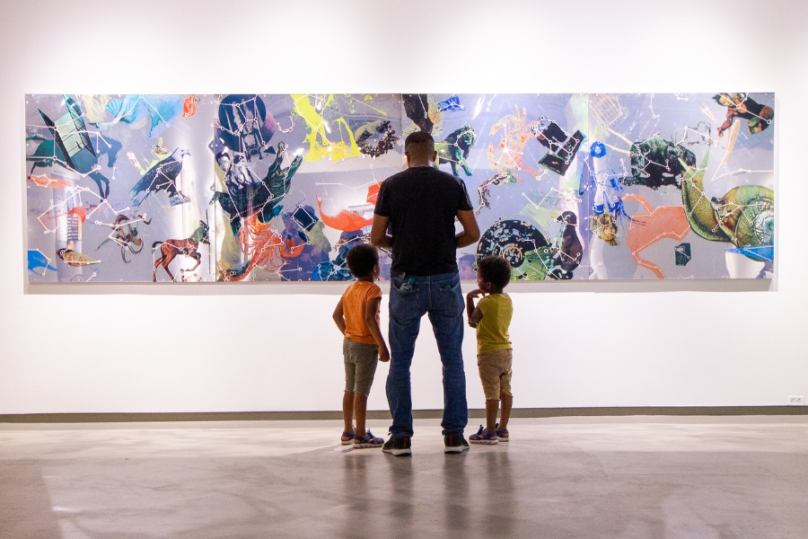 a family stands in front of a Robert Rauschenberg silkscreen on a mirror