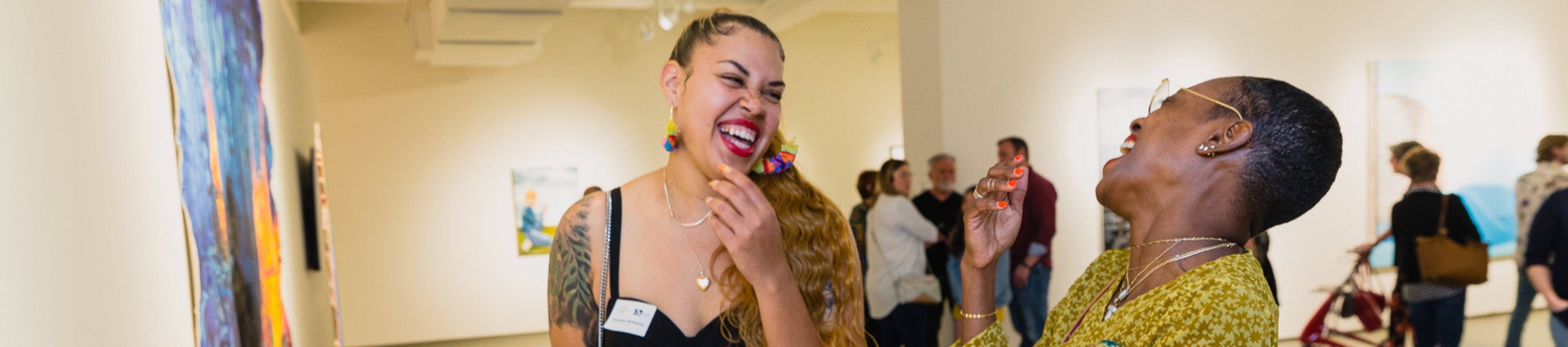 two women at an exhibition opening at MOCA Jacksonville laughing and enjoying themselves