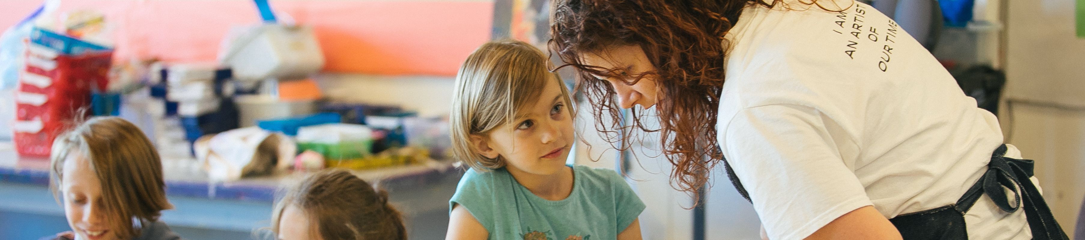 a MOCA Teen Teacher helps a Summer Camp @ MOCA student with an activity