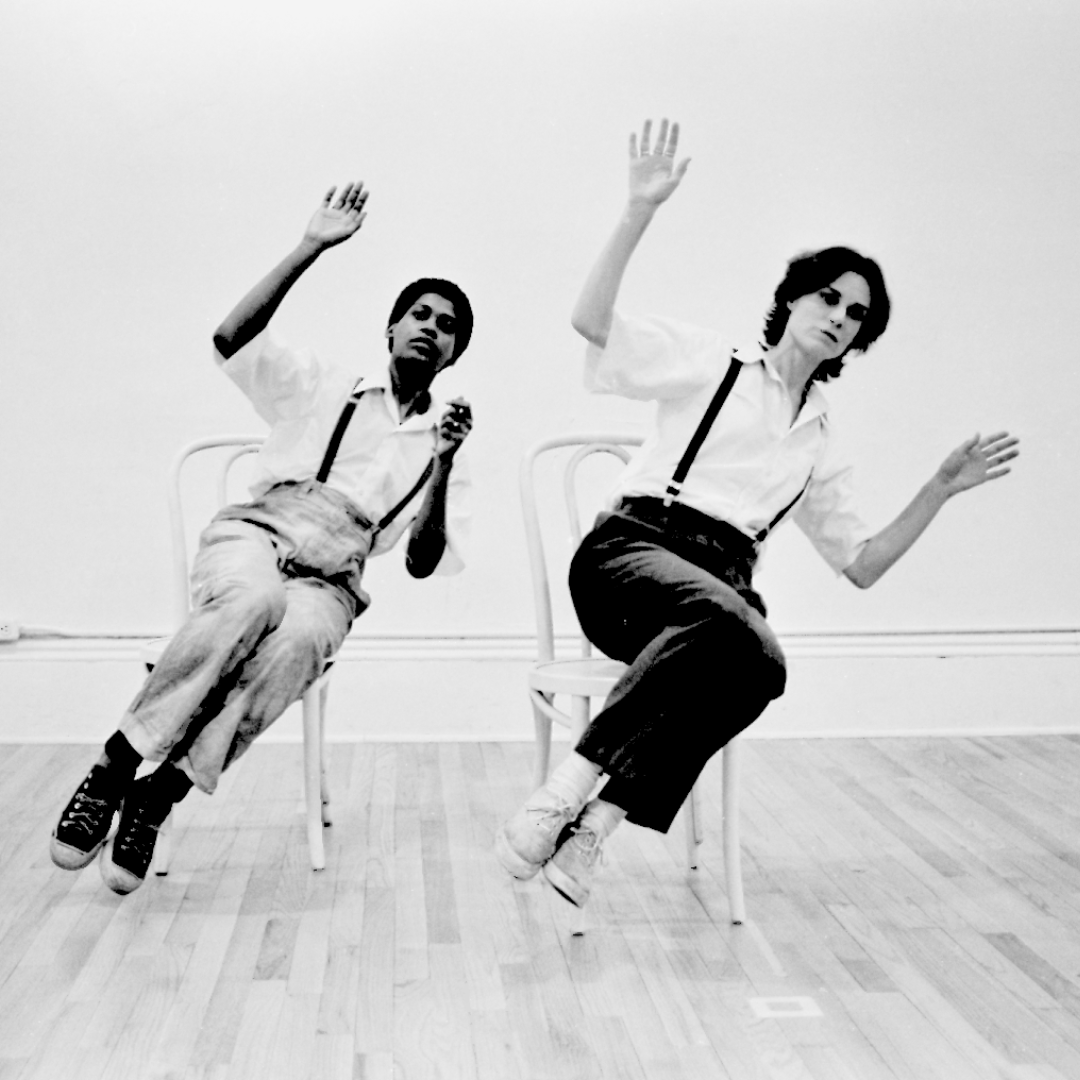 black and white image of two people sitting at a diagonal in chairs with their arms up