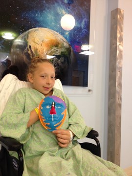 girl in a wheelchair holding her mask