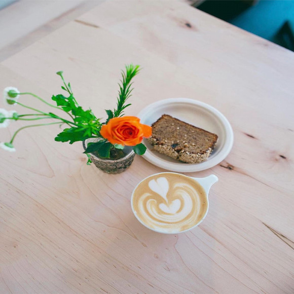 close up of a cup of espresso with a plate of dessert on the side