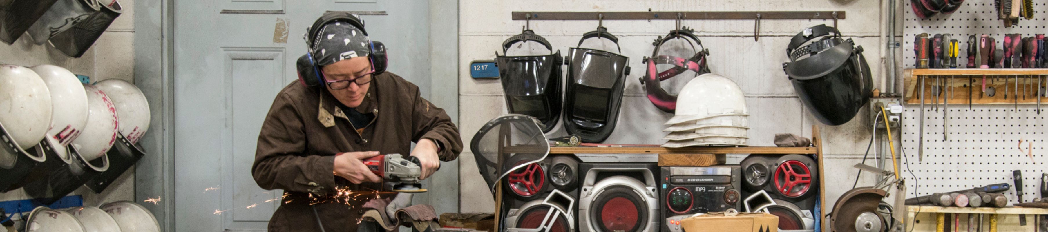 UNF Student Artist-in-Residence Jenn Peek grinds an iron piece in the UNF Sculpture Lab