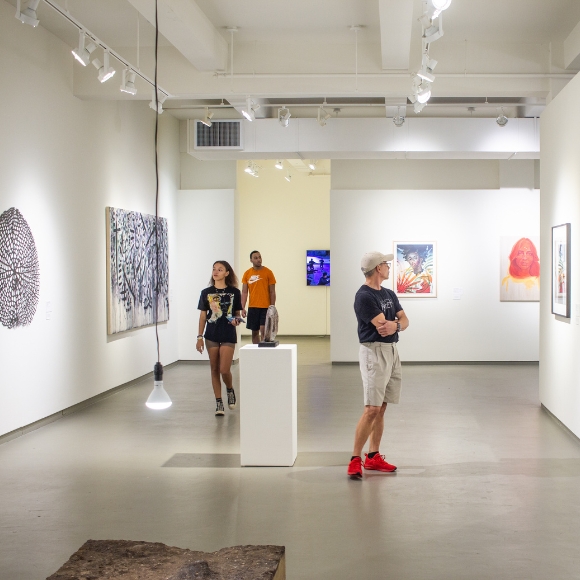 a group of people looking at paintings and sculptures in a gallery